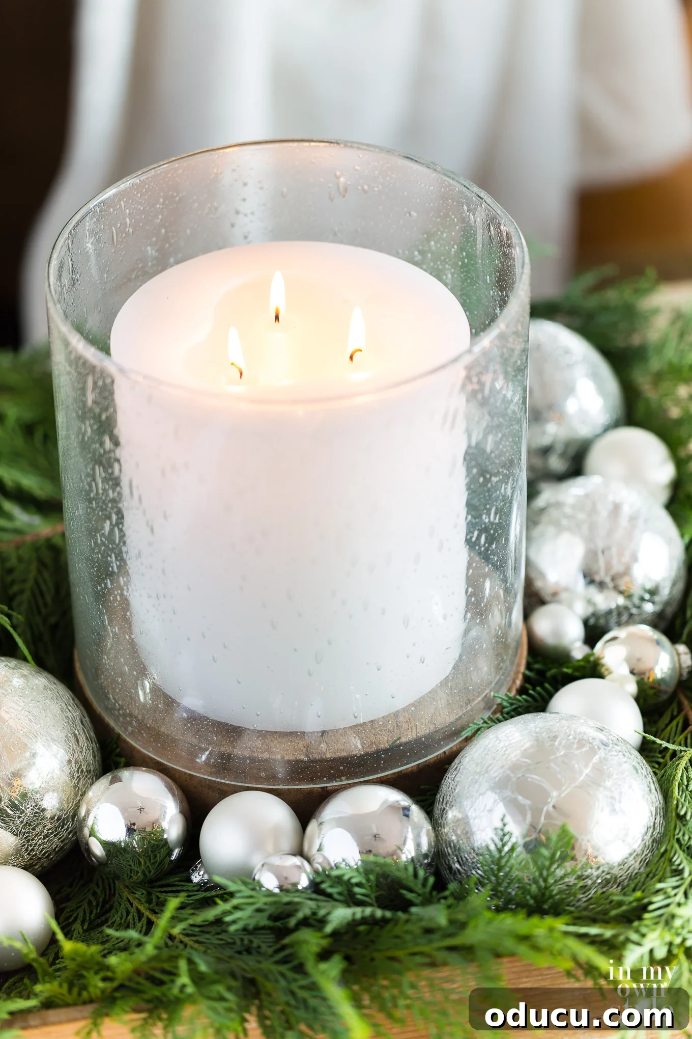 Ideas on how to display candles in a home for the holidays. Bubble glass hurricane and large white candle table decorated for Christmas, exuding calm elegance