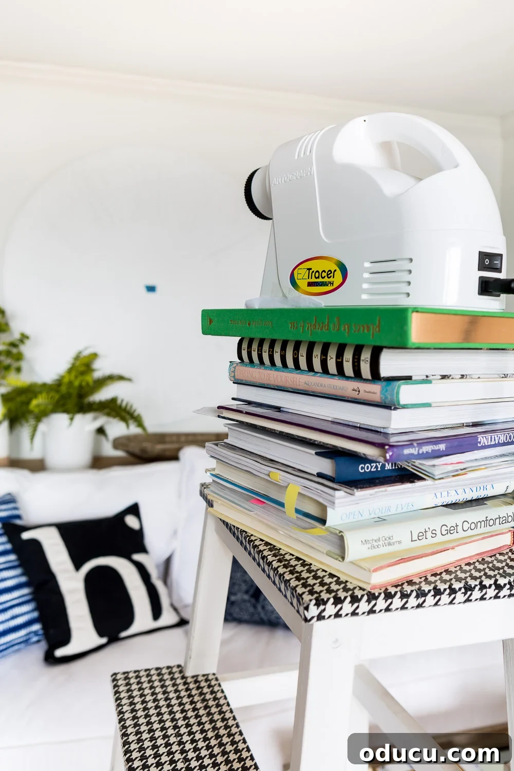 DIY Giant Farmhouse Wall Clock 11 An art projector carefully positioned on a stack of books, preparing to assist in drawing a detailed clock face onto a 48-inch plywood board for a DIY project.