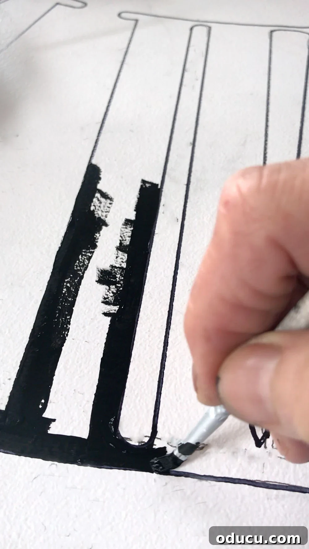 DIY Giant Farmhouse Wall Clock 14 A detailed image illustrating the process of painting black Roman numerals onto a white clock face, step-by-step for a DIY oversized clock.