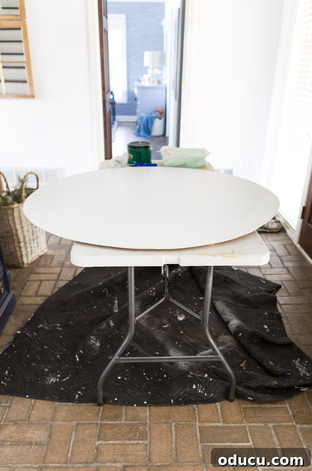 DIY Giant Farmhouse Wall Clock 7 A large plywood circle being painted with a roller, illustrating the first step in creating an oversized clock face for a DIY project.