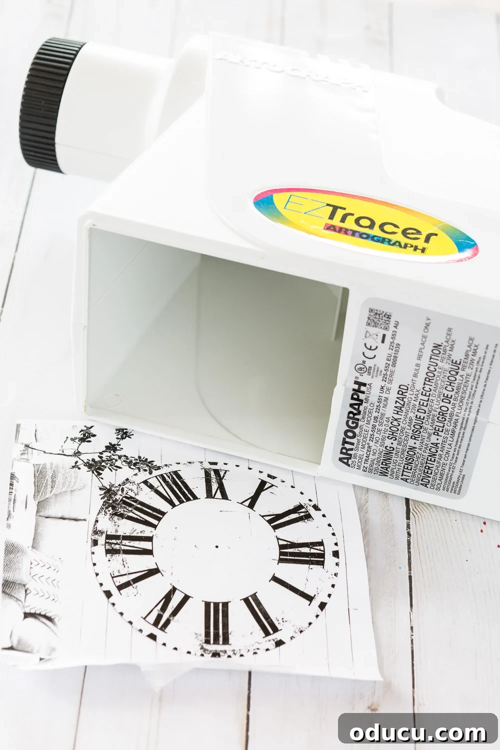 DIY Giant Farmhouse Wall Clock 9 A small EZ Tracer Art Projector illuminating a desk, ready to enlarge an image for tracing onto a large canvas or wall, perfect for DIY murals or clocks.