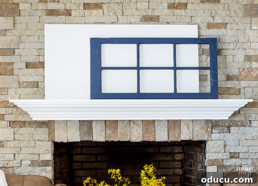Decorate a Mantel You Can Be Proud Of when using the principles of design. A layered mantel arrangement featuring a large white canvas and an old navy blue glass cabinet door, creating depth and visual interest.