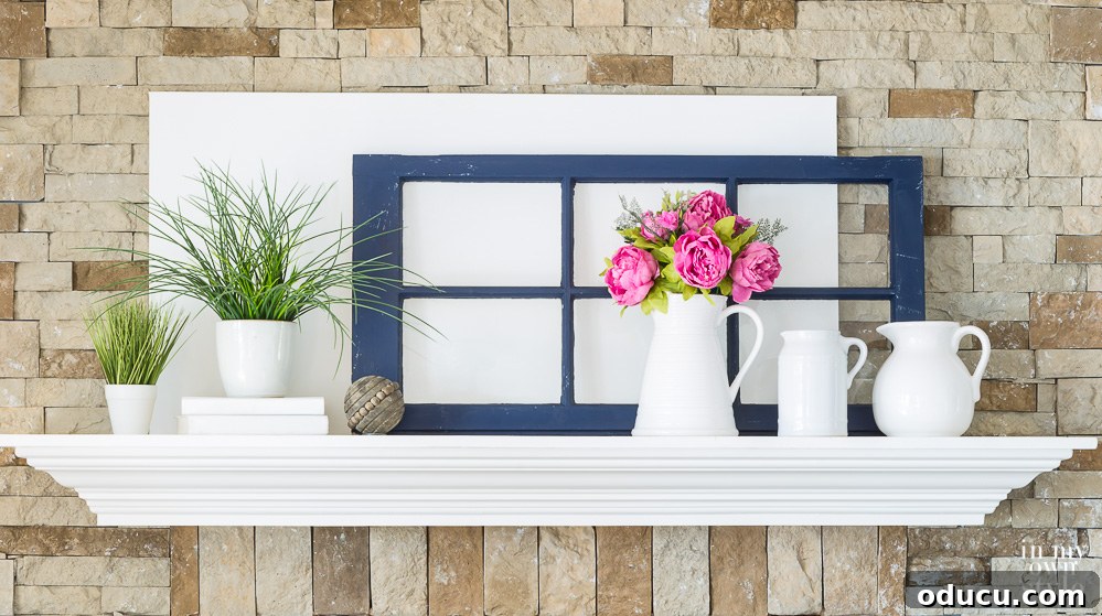 White and navy blue decorated mantel for spring. A balanced spring mantel adorned with white and navy blue elements, accented with pops of pink and green, creating a fresh and vibrant display.