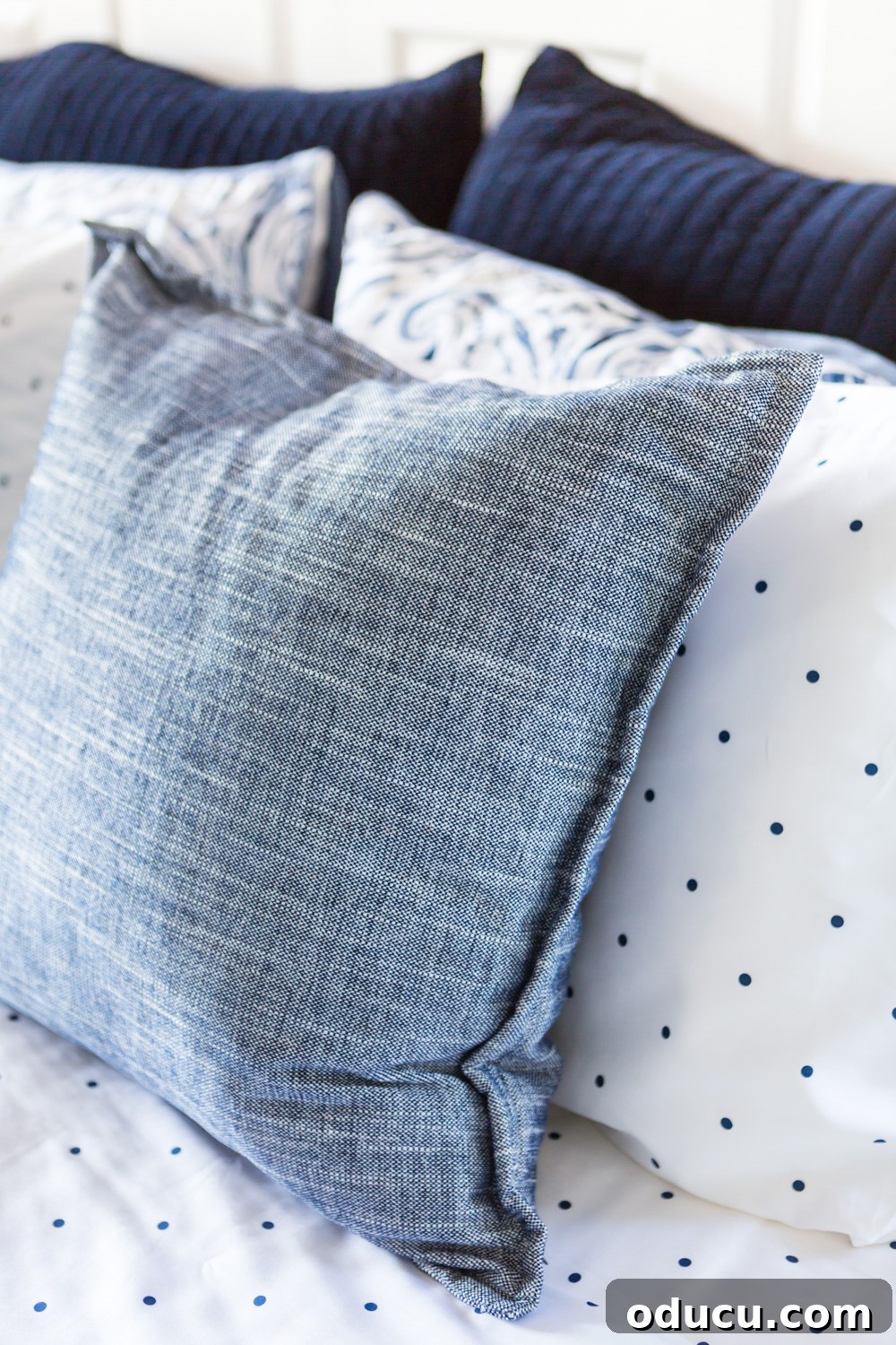 Embracing the SLOW Method for Mindful Decorating 4 Close-up of a stylish blue and white decorative pillow on a neatly made bed