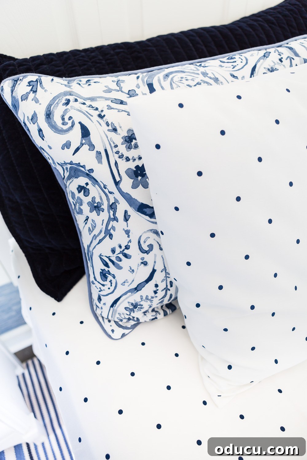 Embracing the SLOW Method for Mindful Decorating 6 Beautifully arranged bed pillows in a harmonious navy and white color scheme, featuring polka dot sheets