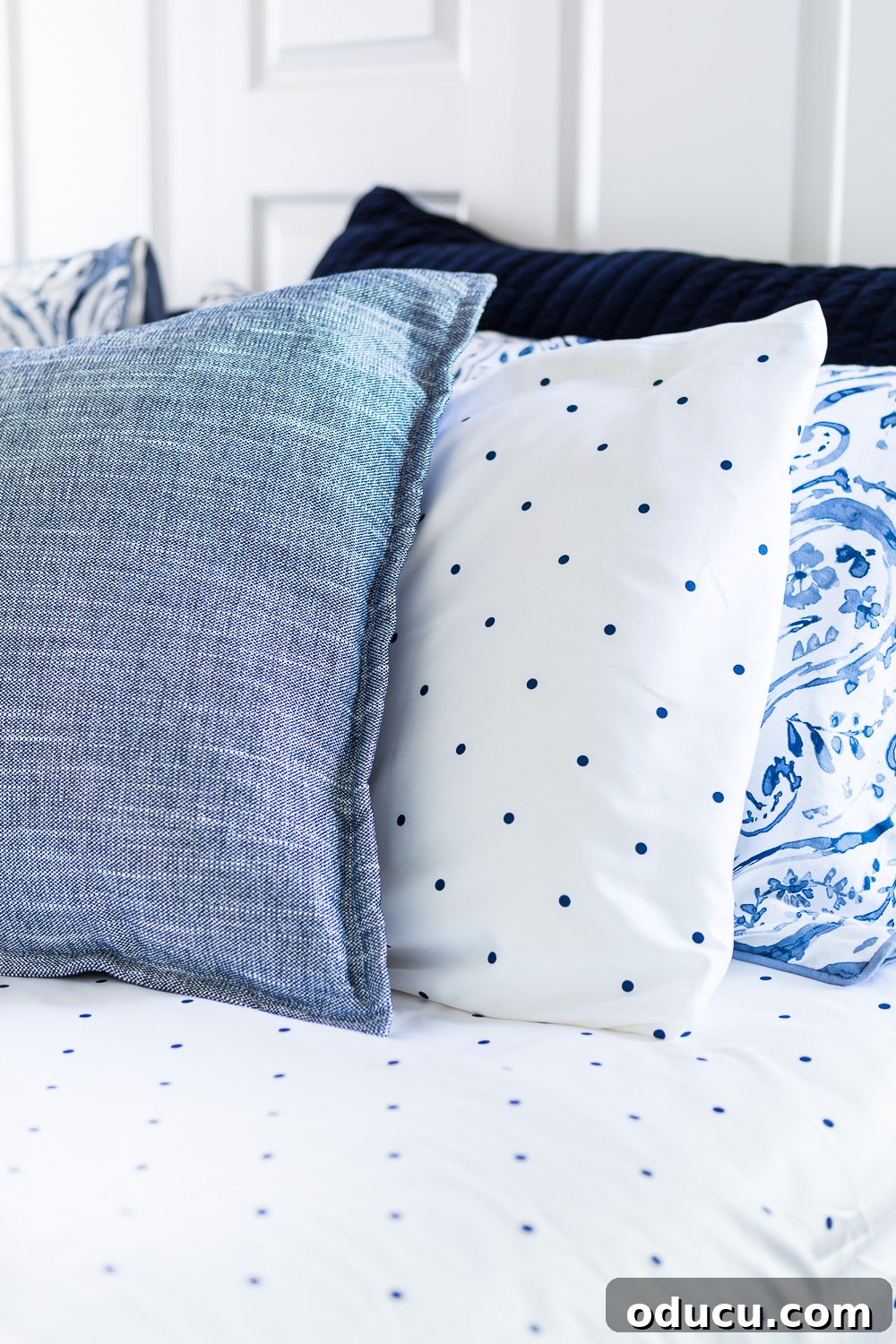 Embracing the SLOW Method for Mindful Decorating 9 Three perfectly arranged blue and white bed pillows resting on a soft bed, showcasing comfort and style