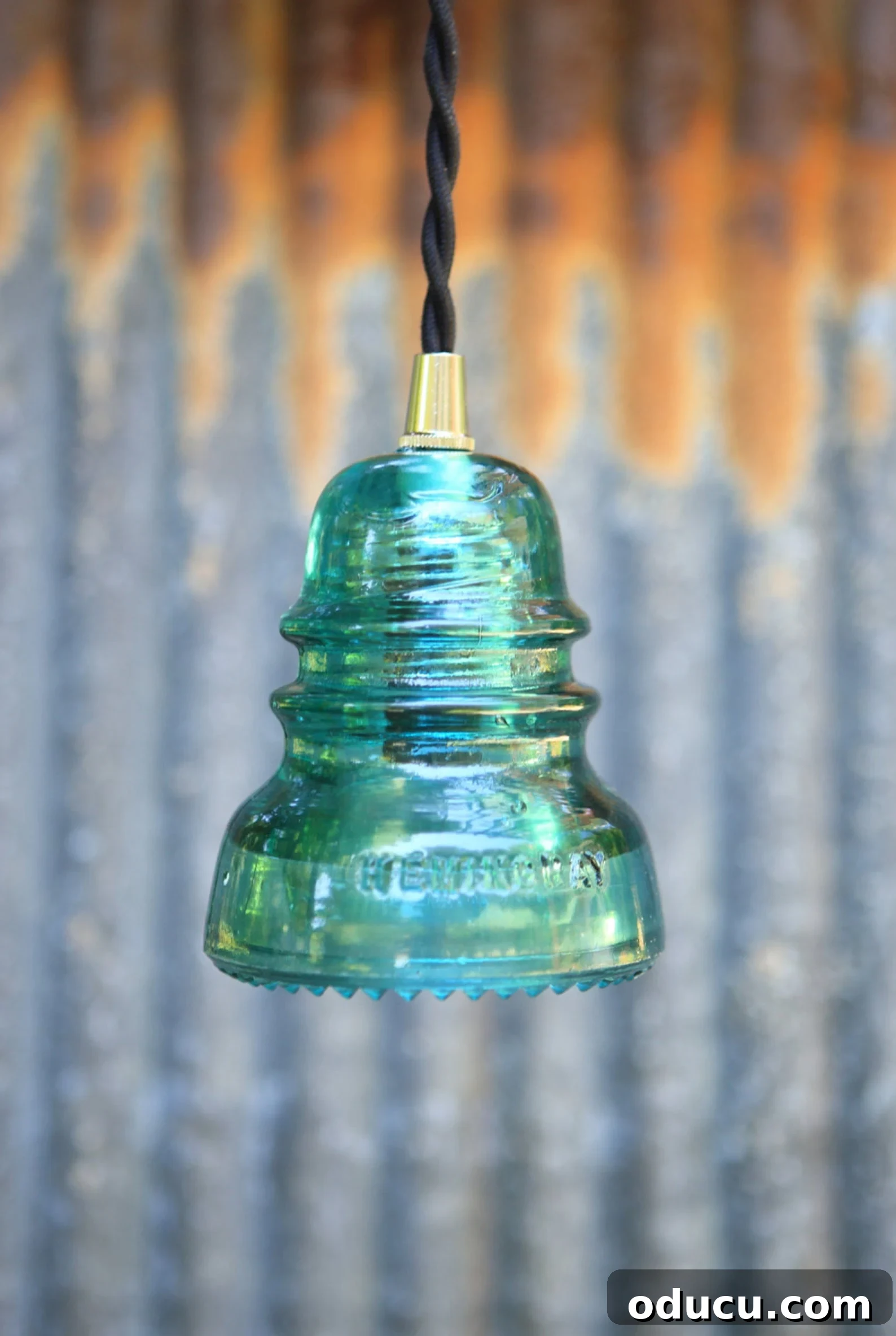 Echoes in Every Element 8 An aqua glass insulator creatively transformed into a stylish pendant light, showcasing its versatility in home decor.