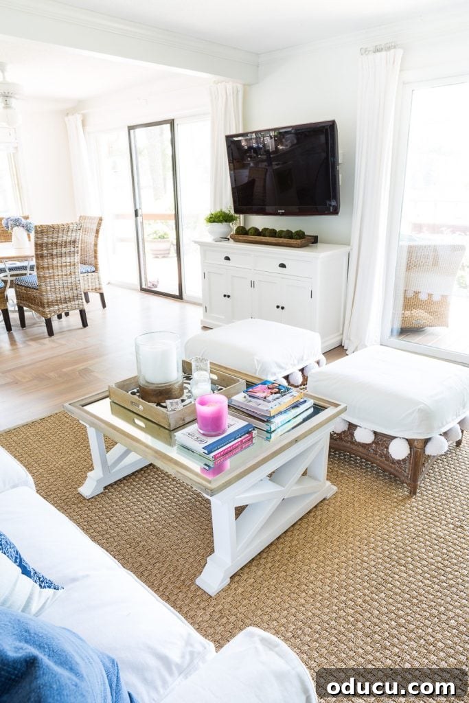 Ottomans: From Footrest to Focal Point 4 A beautifully designed living room with a conversational furniture layout, enhanced by a pair of identical ottomans and a seagrass area rug that defines the seating space.