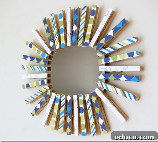How to make a colorful starburst mirror made using clothespins and scrapbook paper. Blue green and white starburst mirror