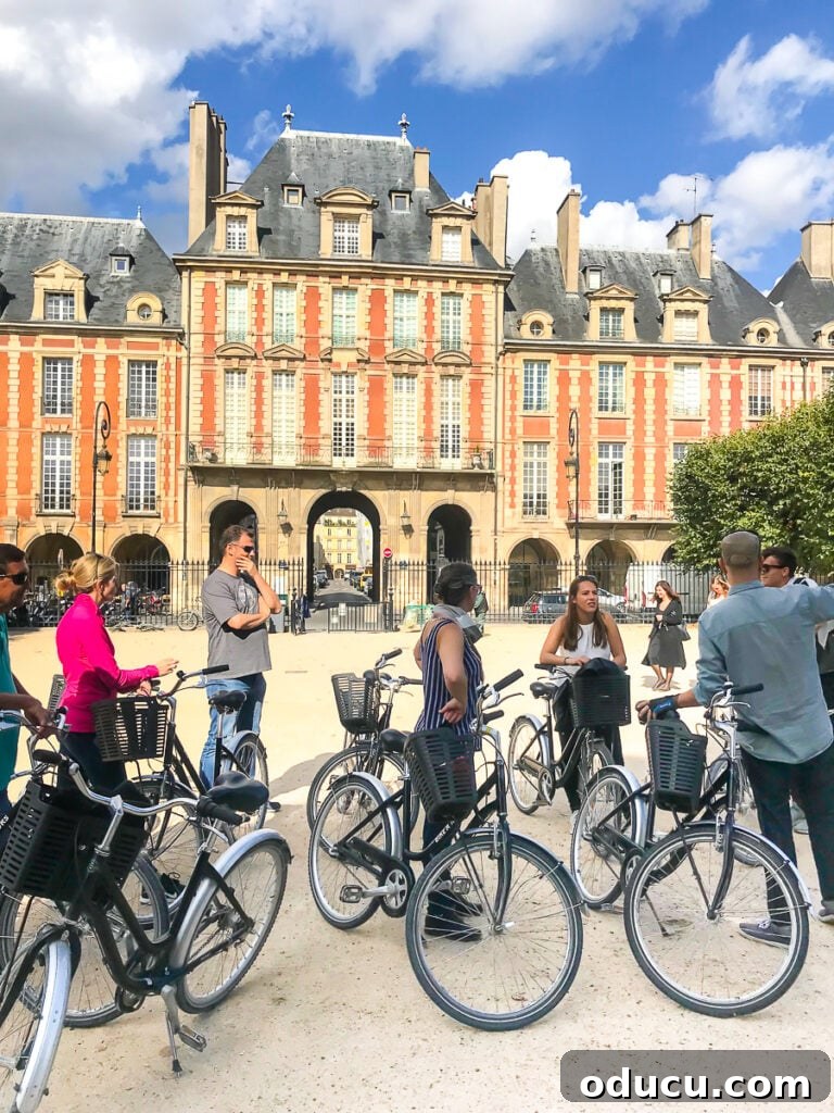 A guided bike tour in Paris pauses at the historic Place des Vosges, offering a serene break in the Marais district amidst elegant architecture.