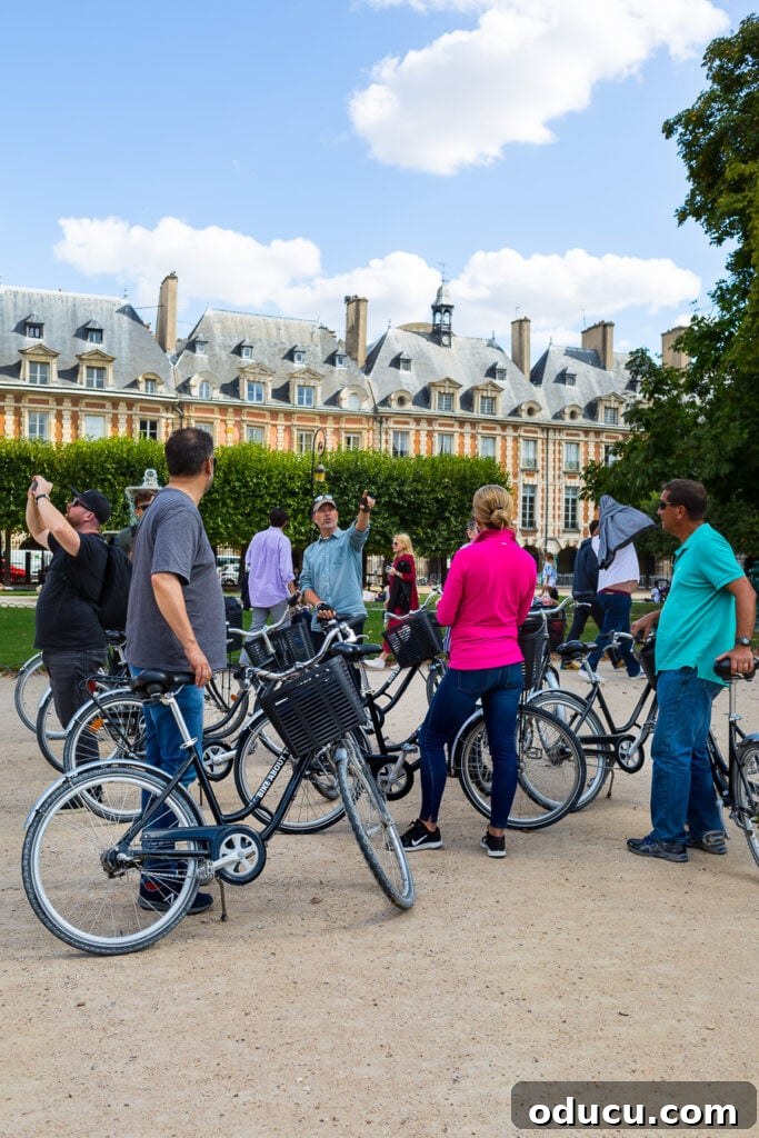 Bike About Tours Paris guiding us through the historic and picturesque Place des Vosges in the Marais district, revealing its unique charm.