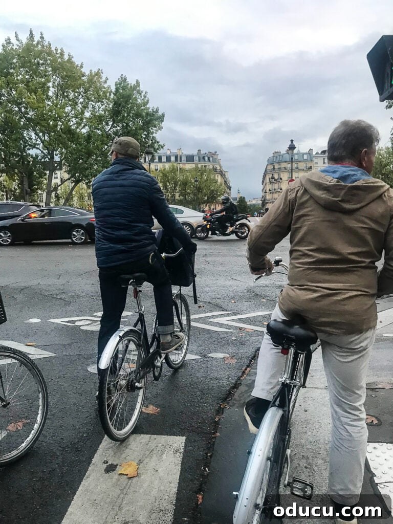 Simon from Bike About Tours skillfully leading a group of excited tourists on bikes through the charming back streets of Paris at night, under city lights.