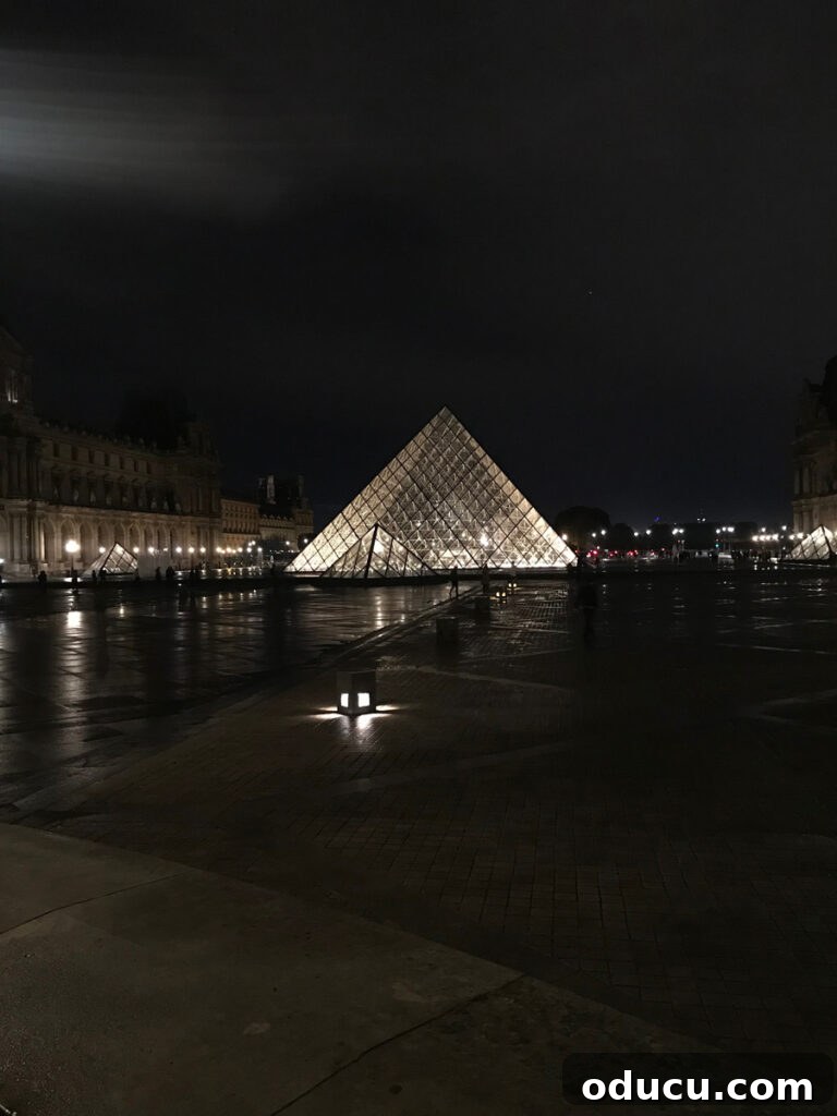 The iconic glass pyramid at the Louvre, beautifully illuminated at night, creating a stunning visual effect and a modern glow.