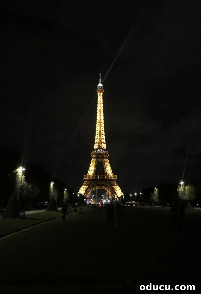 The iconic Eiffel Tower magnificently lit up and twinkling at night, a truly spectacular and romantic sight in Paris, dazzling all who behold it.