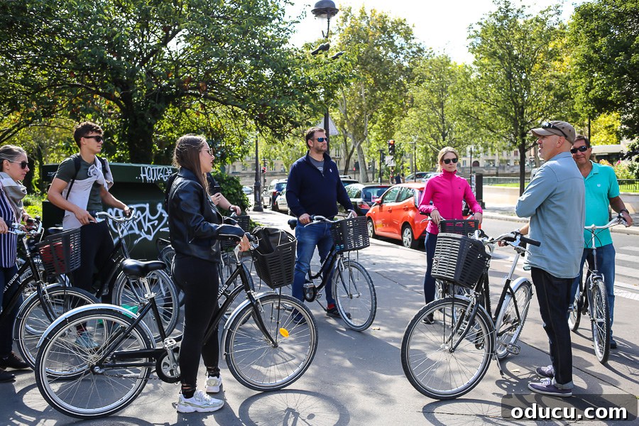 Simon, the charismatic tour guide from Bike About Tours Paris, engaging with his enthusiastic group of cyclists, sharing insights and laughter.