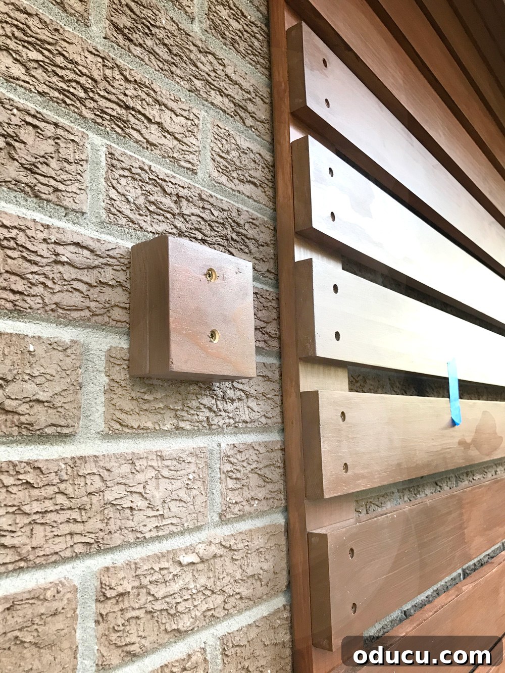 Wood blocks mounted on a brick wall, preparing the surface for an address plate to align with a slat wall.