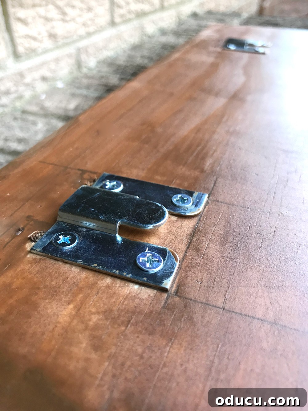 Detailed view of a slide-in hanger attached to the back of an address plate, ready for mounting.