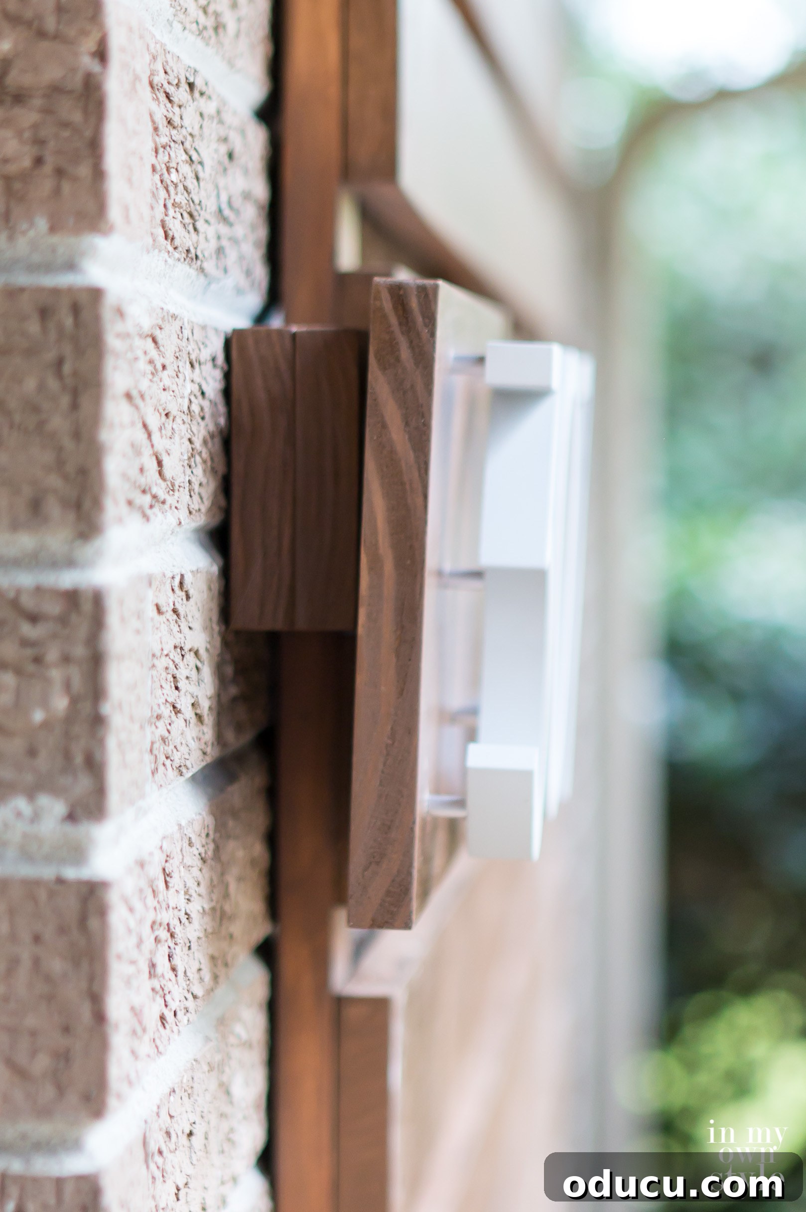 Side view demonstrating how the modern house address plate is securely mounted onto the exterior brick wall using flush hangers.