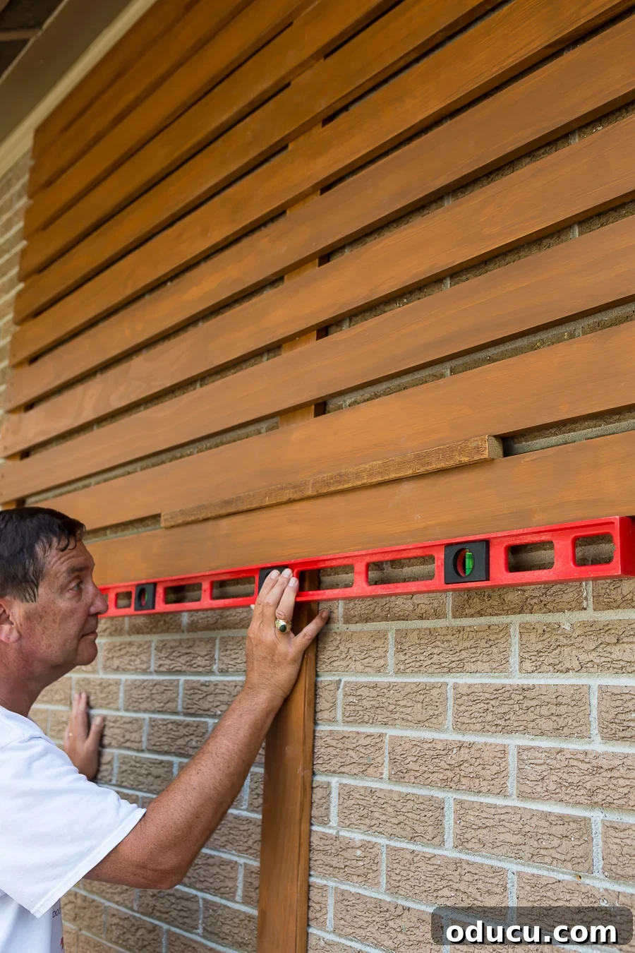 How to level wood slats when making an outdoor slat wall or privacy fence, demonstrating the use of a spacer.