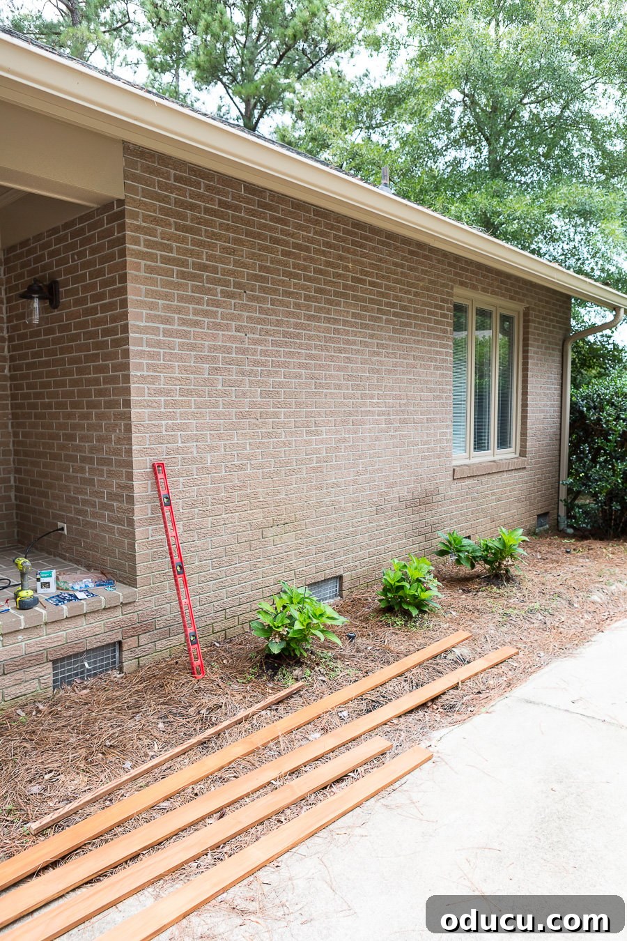How to prep a brick wall to build an exterior horizontal wood accent wall, showing the center marked with tape.
