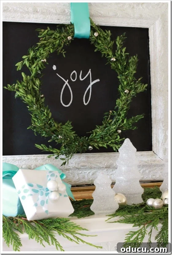 Christmas mantel with chalkboard featuring the word 'joy' written on it, surrounded by festive decor