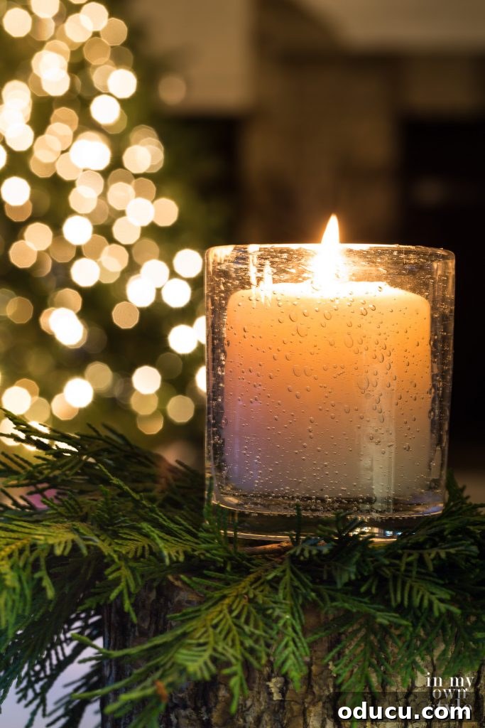 Candle glowing in front of a Christmas tree with white lights, symbolizing peace and simplicity