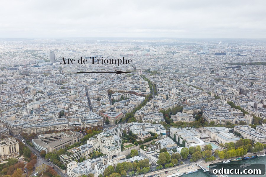 Ascending Paris's Masterpiece 5 A stunning bird's-eye view of Paris from the Eiffel Tower, with iconic landmarks spread across the cityscape under an overcast sky.