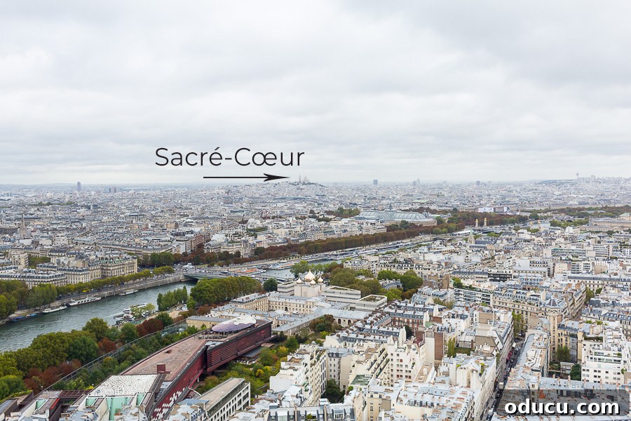 Ascending Paris's Masterpiece 7 The Sacré-Cœur Basilica visible in the distant Parisian cityscape, as seen from the Eiffel Tower.
