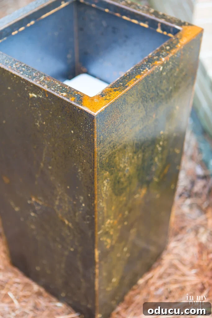 Unlock Corten's Rustic Beauty Instantly 7 First coat of rust accelerator applied to the surface of a metal planter, showing initial reaction.