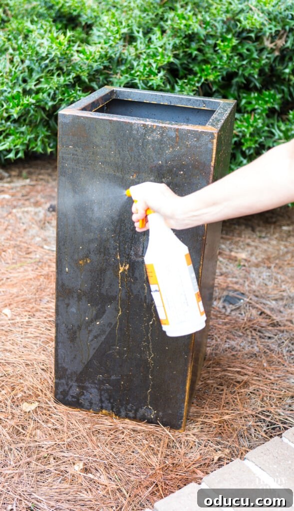 Unlock Corten's Rustic Beauty Instantly 8 First coat of rust accelerator being applied with a spray bottle on the surface of a metal planter, demonstrating the application technique.