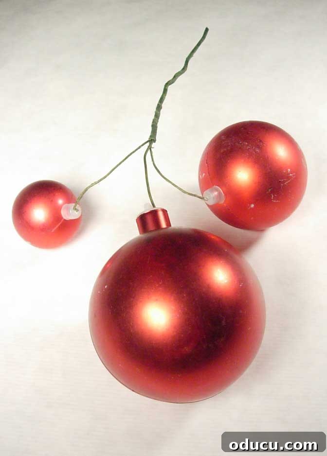 How to decorate a Christmas garland A lush Christmas garland decorated with clusters of red and silver ball ornaments, intertwined with twinkling lights, draped over a mantelpiece, showcasing elegant holiday home decor.