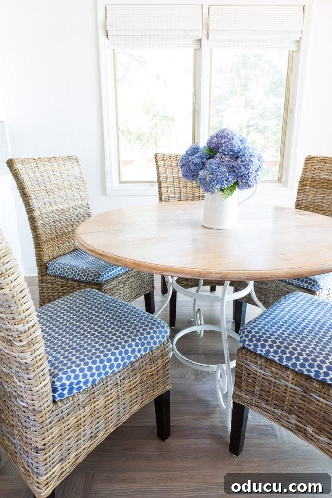 Wood-Effect Dining Table Upgrade 4 Round wood kitchen table with light driftwood colored woven chairs, showcasing a light wood table finish.