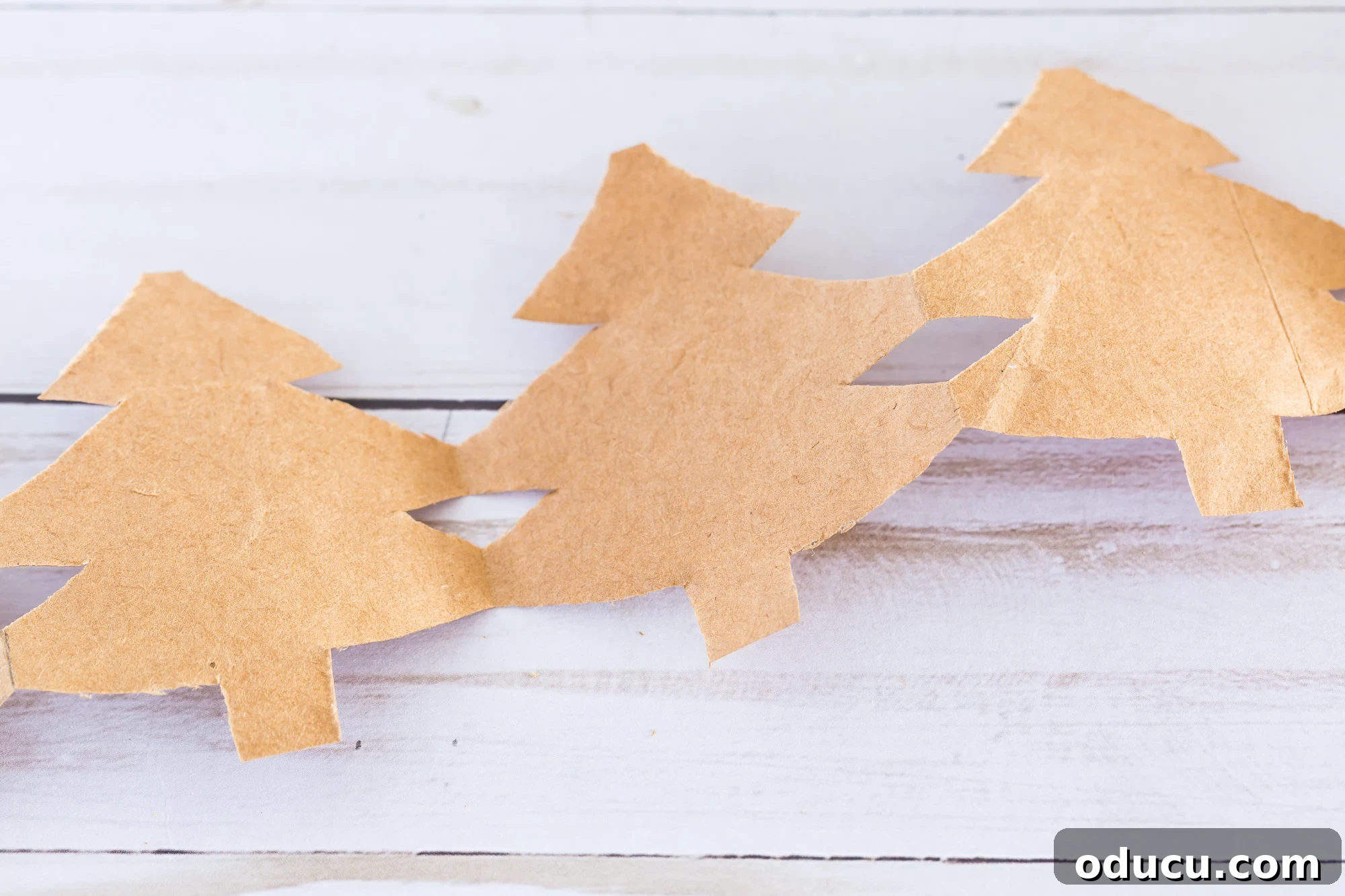 Craft Your Own Christmas Tree Paper Chain 13 Christmas Tree paper chain made using a brown paper bag unfolded to reveal Christmas tree shaped design.