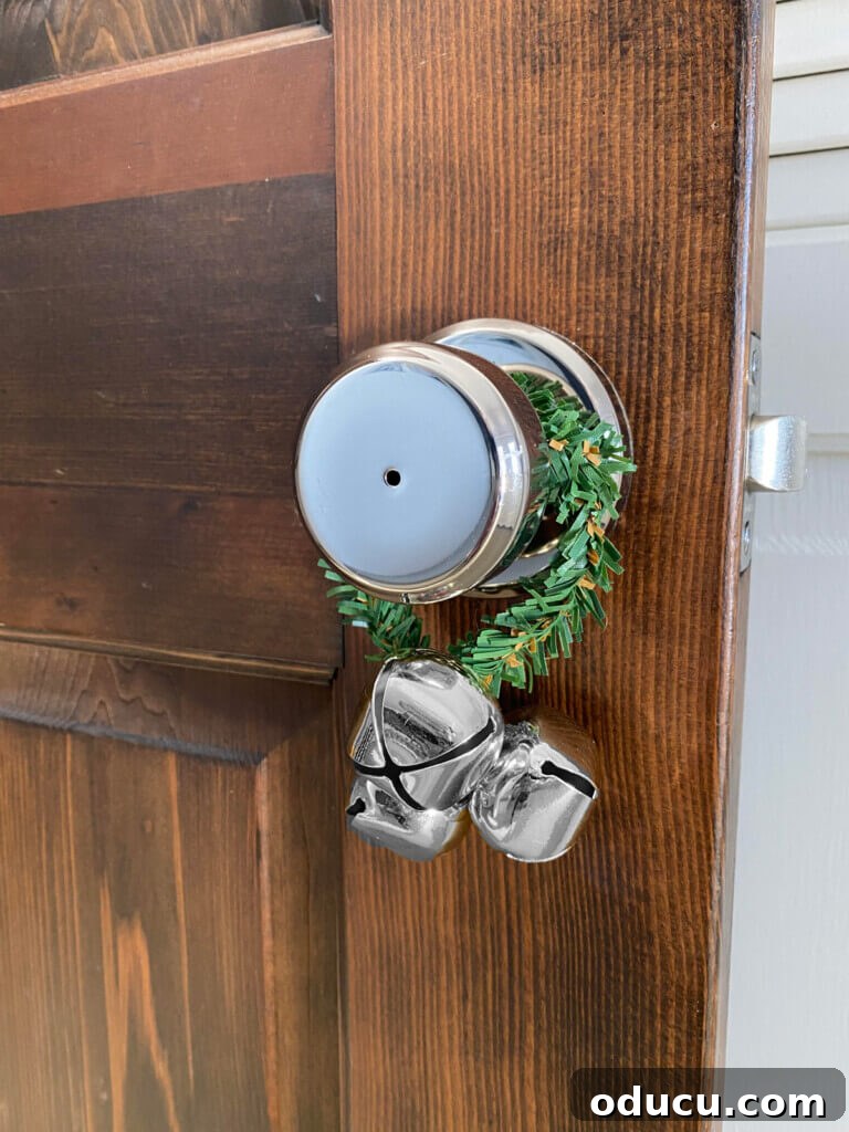 Quick Christmas Home Decor Hacks When Time is Tight 18 Christmas garland tie around a doorknob with a jingle bell attached.