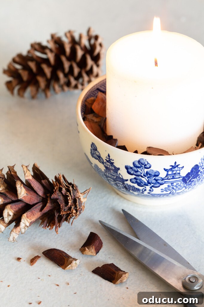 Quick Christmas Home Decor Hacks When Time is Tight 7 small blue and white bowl with white candle and pieces of a pine cone.