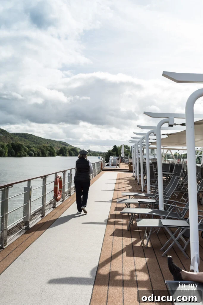 An Iconic Viking Journey Along the Seine 12 A person walking along the top deck of a Viking River Cruise Longship on the Seine in France, enjoying the open air.