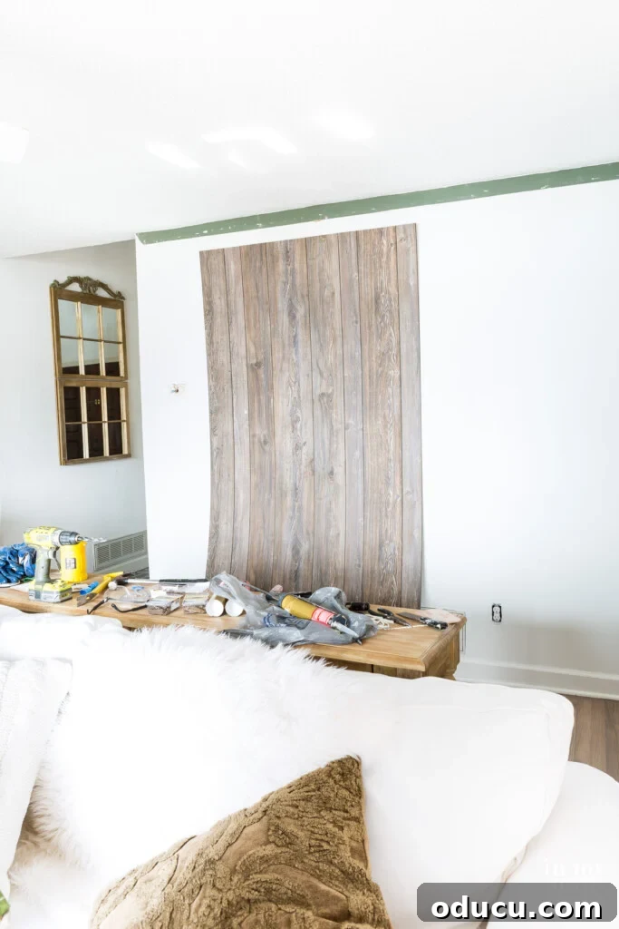 Dramatic Living Room Transformation 4 Installing barnwood sheet paneling to a living room accent wall, demonstrating a DIY home decor project