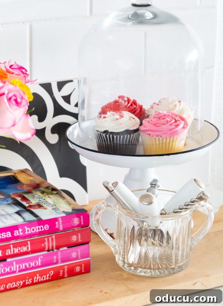 Transform Your Kitchen Counters: 4 Quick Styling Tips 7 cupcakes under a glass dome cake stand on a kitchen counter.