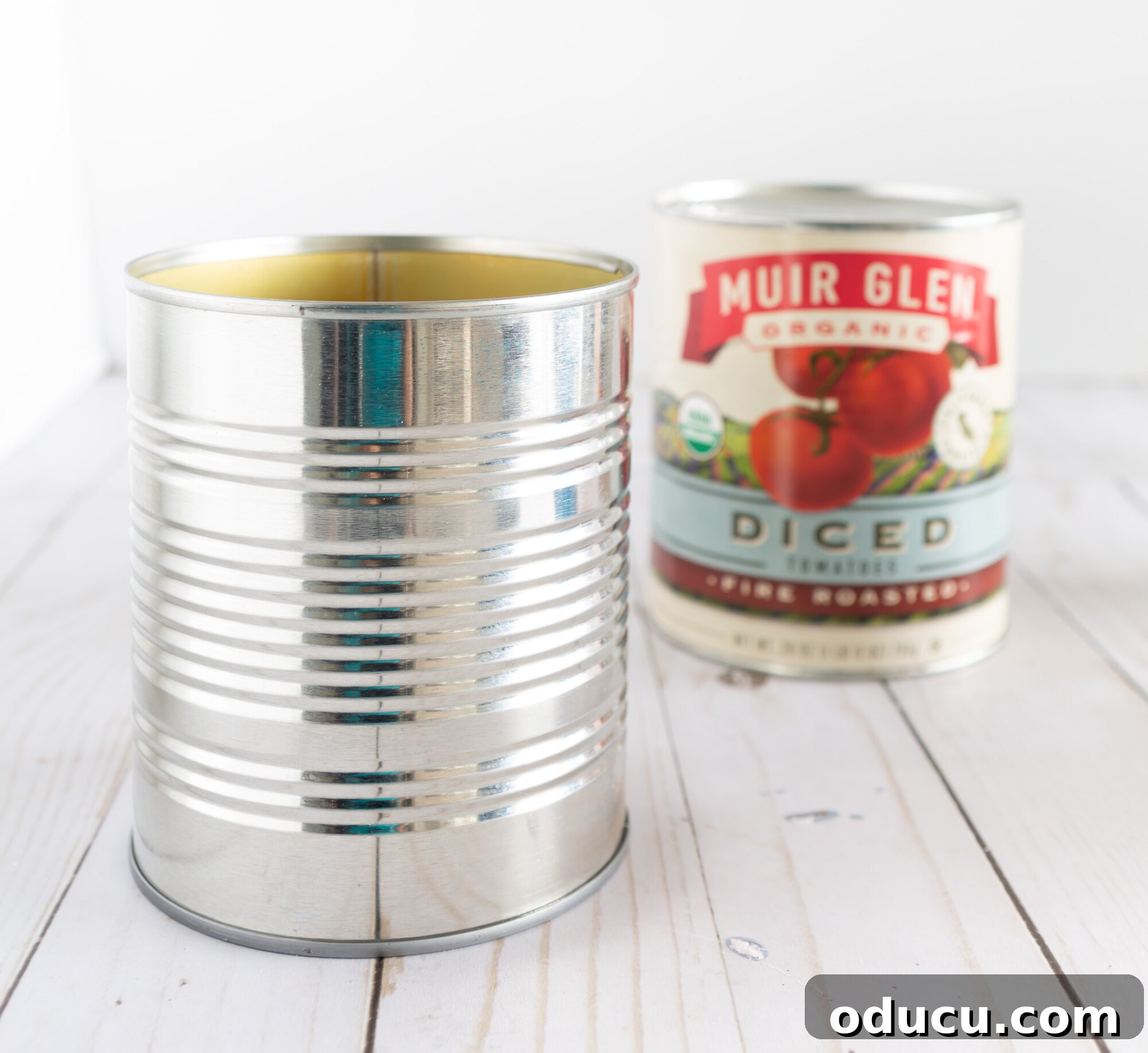 Tin can shown with the paper label off next to one that still has the label.