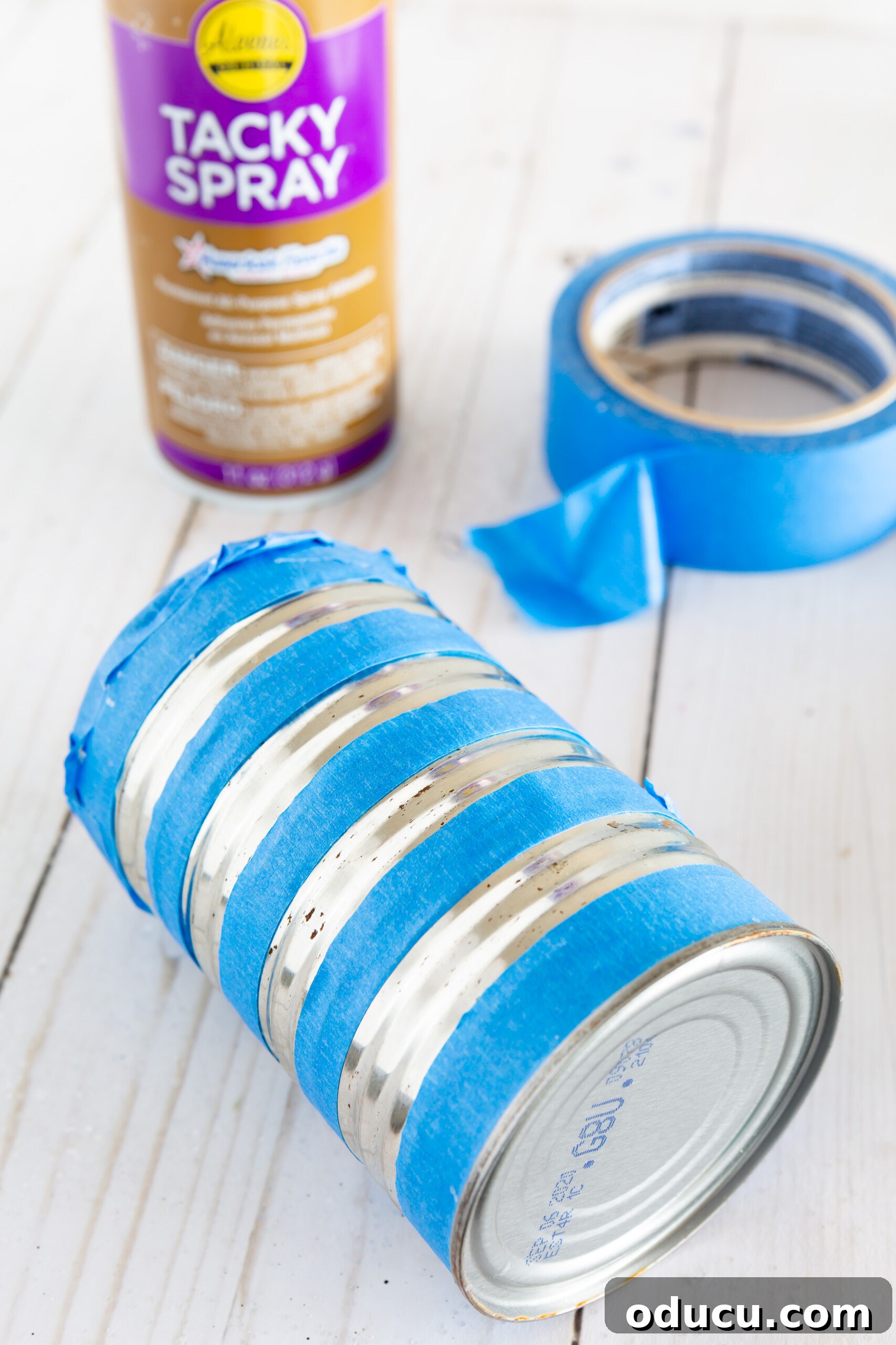 applying tape to a tin can to create glitter stripes to make a vase.