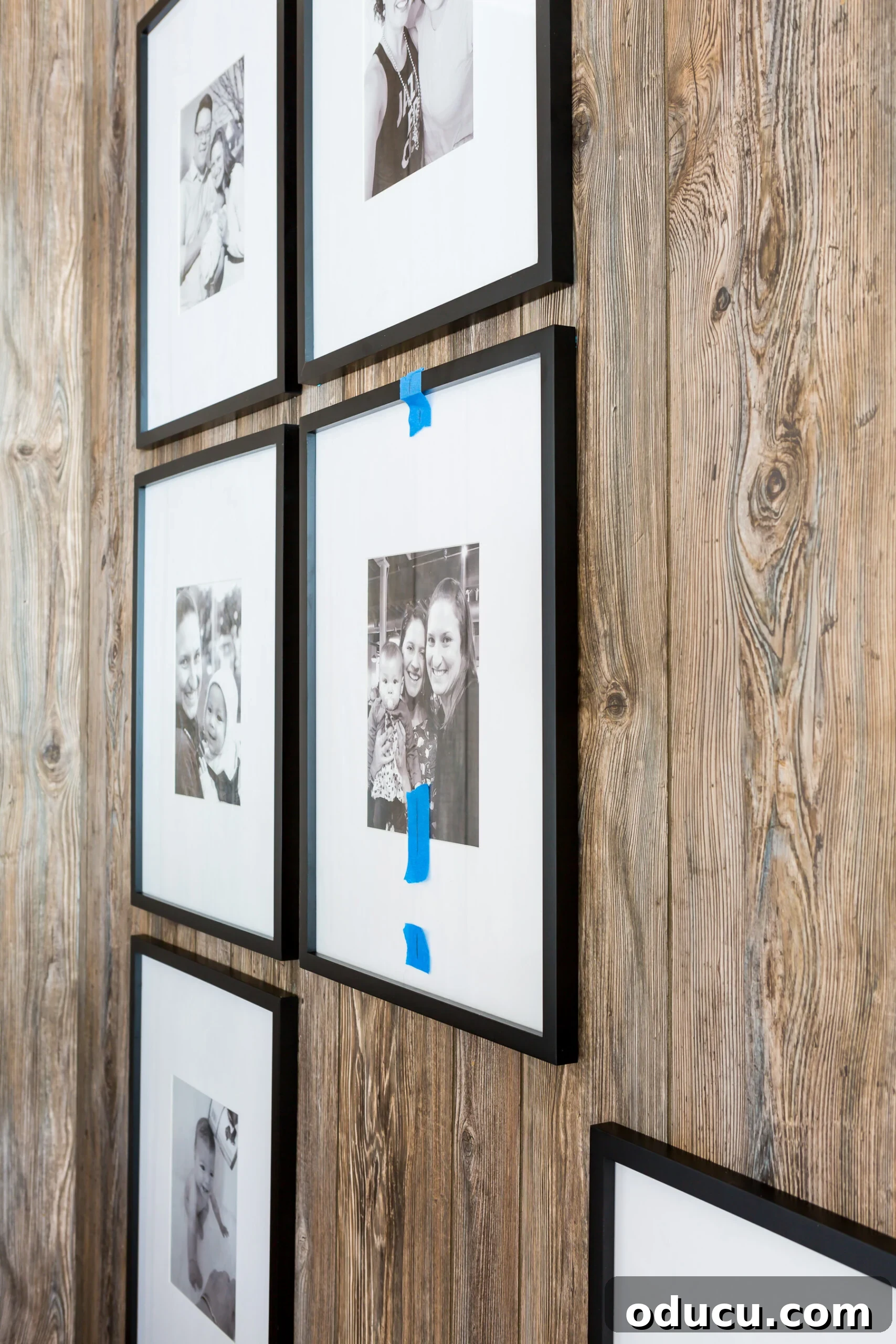 Hanging frames in a grid style on a paneled wall, focusing on the first central frame placement.