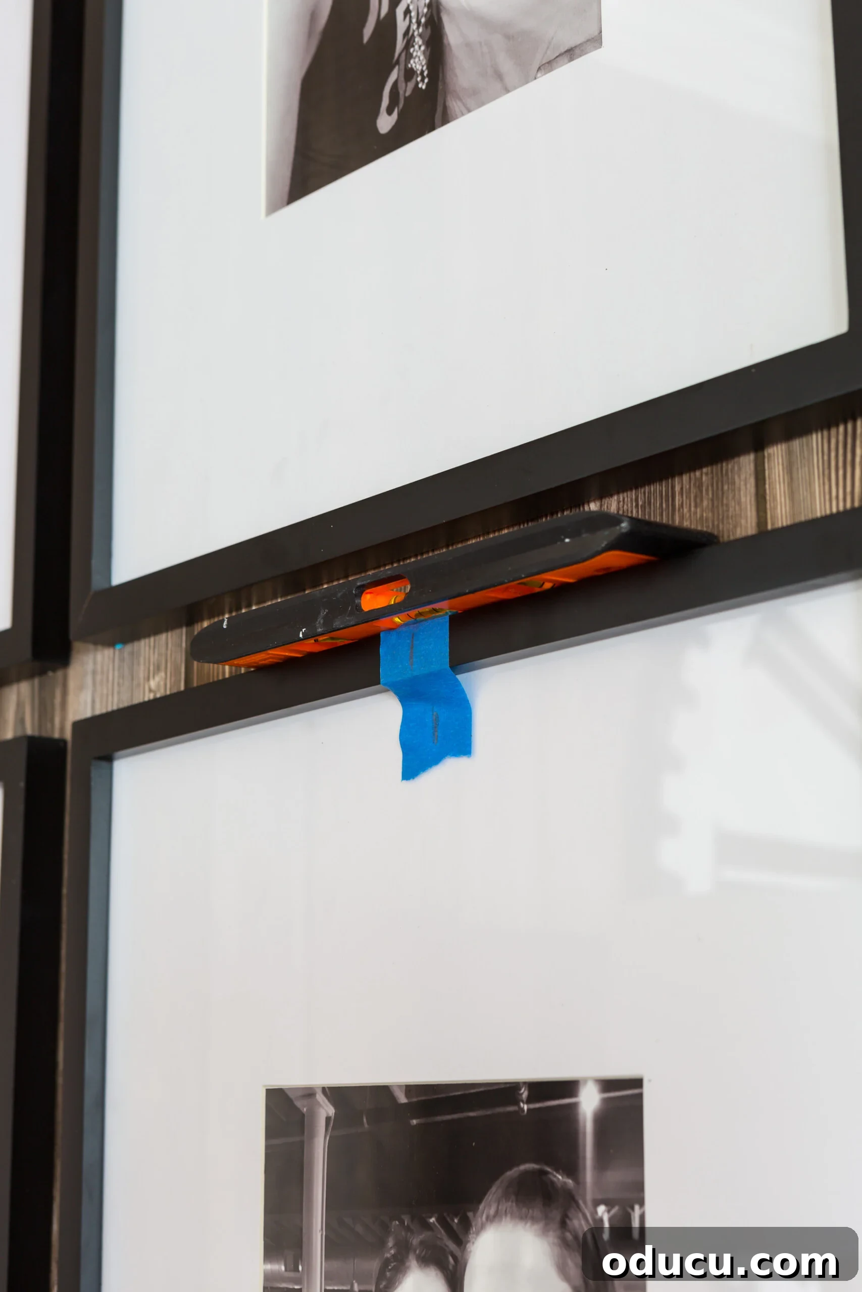How to level photo frames in a grid pattern on a wall using a bubble level for accurate alignment.