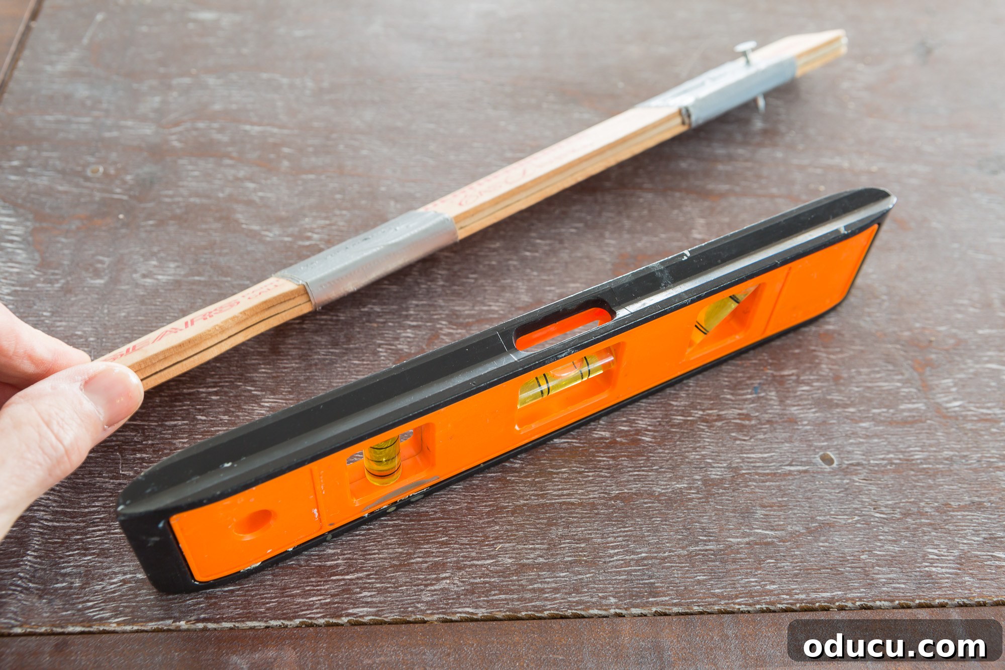 Basic tools to use to hang a gallery wall evenly and level, highlighting the DIY picture hanging tool.