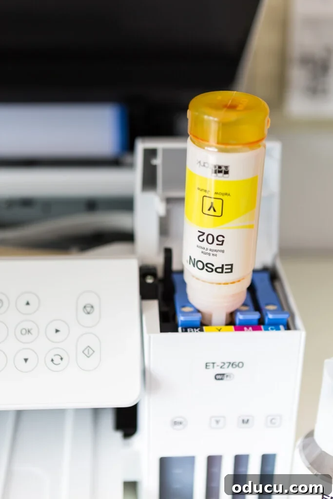 Close-up of an Epson photo printer being filled with ink from a bottle.