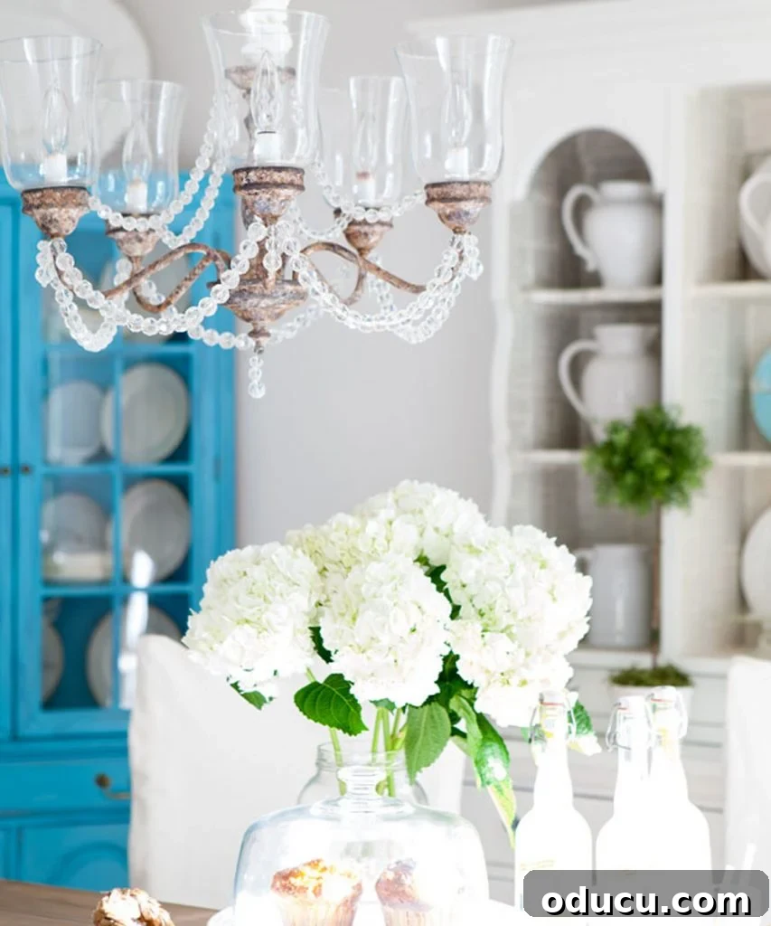 Decorating Wisdom That Changed Everything 2 Elegant white and turquoise dining room with a rustic crystal chandelier, exuding a serene and inviting atmosphere.