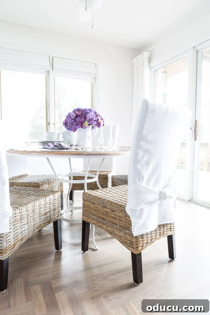 Awaken Your Home For Spring 15 Casual and simple spring decorating for a dining room. Rattan chairs with white slipcovers on the backs. Round wood table with white wrought iron base.