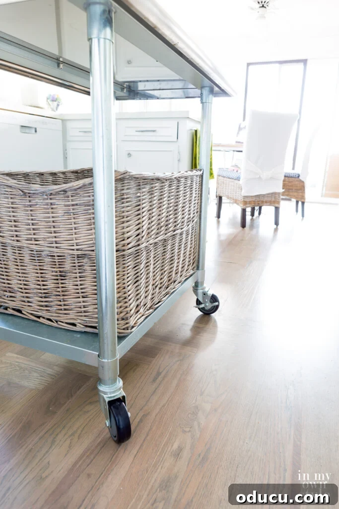 Movable metal rolling island in a small white kitchen showcasing clever storage.