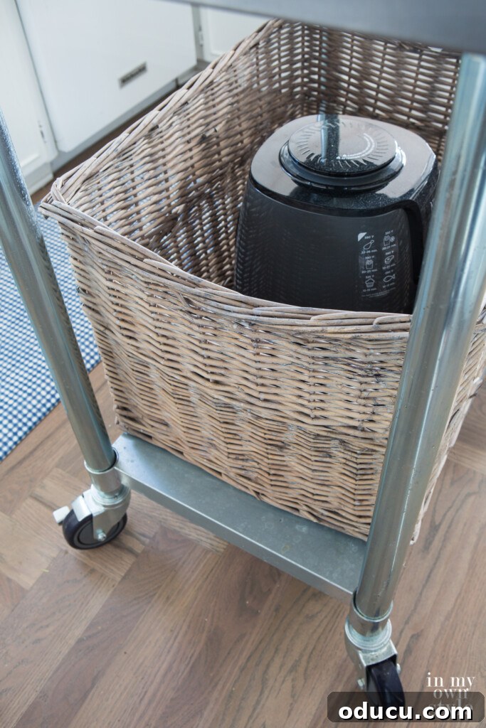 Large grey Kubu style storage basket on rolling kitchen island, providing concealed storage.