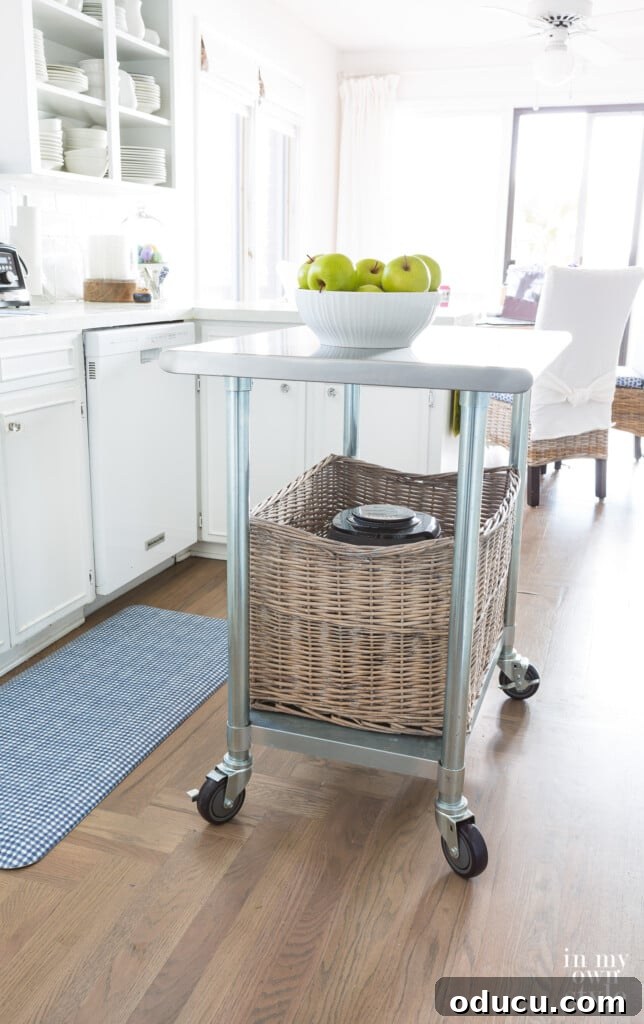 Metal rolling kitchen island with large rattan basket on bottom shelf for organized storage.