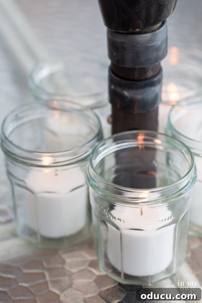 Effortless Chic Patio Umbrella Centerpiece 6 Jelly jars with candles in them around an umbrella pole on a dining table.
